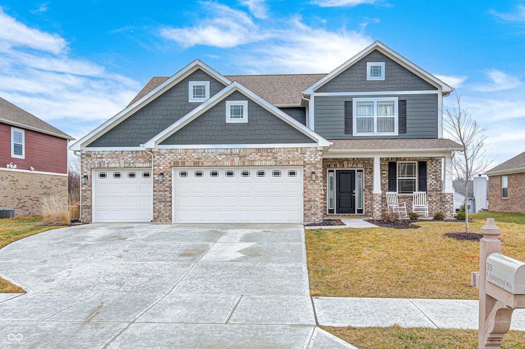 craftsman-style house featuring a garage, covered porch, and a front yard