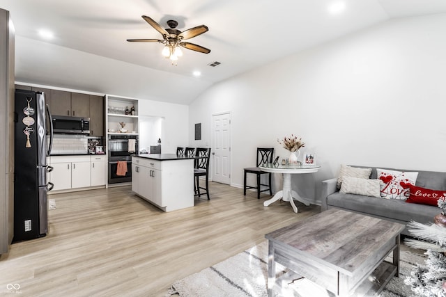 living room featuring vaulted ceiling, light hardwood / wood-style floors, and ceiling fan