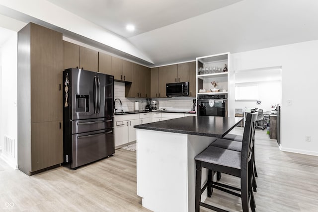 kitchen with light hardwood / wood-style flooring, stainless steel appliances, a center island, a kitchen bar, and decorative backsplash