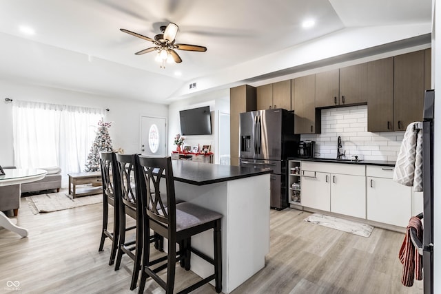 kitchen with vaulted ceiling, white cabinetry, sink, dark brown cabinetry, and stainless steel refrigerator with ice dispenser