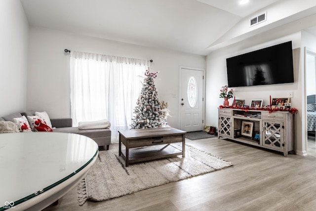 living room featuring lofted ceiling and light hardwood / wood-style flooring