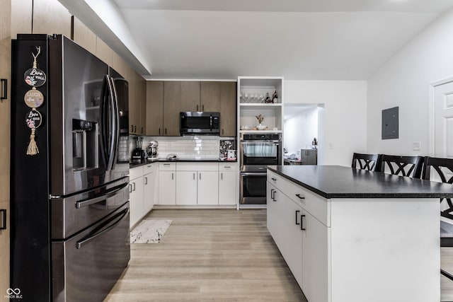 kitchen with a breakfast bar area, appliances with stainless steel finishes, white cabinetry, electric panel, and a kitchen island