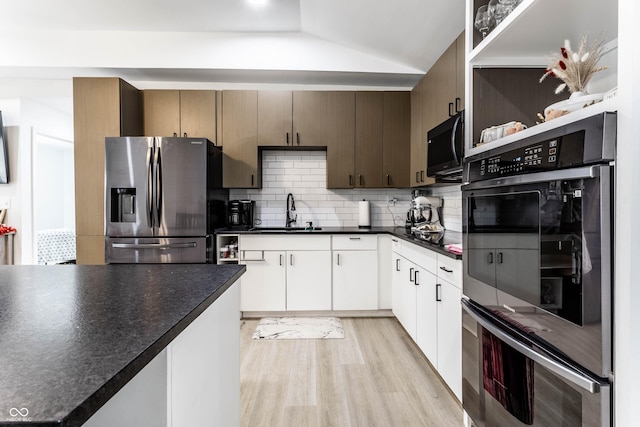 kitchen with sink, white cabinetry, stainless steel appliances, light hardwood / wood-style floors, and decorative backsplash