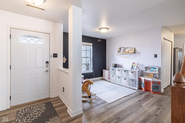 foyer entrance with visible vents, baseboards, and wood finished floors