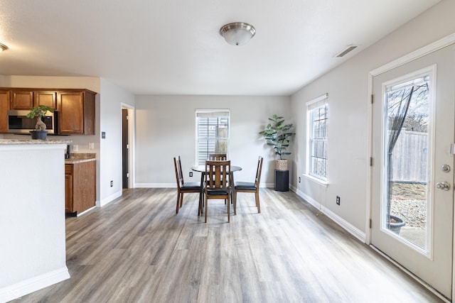 unfurnished dining area with light wood-type flooring, visible vents, and baseboards