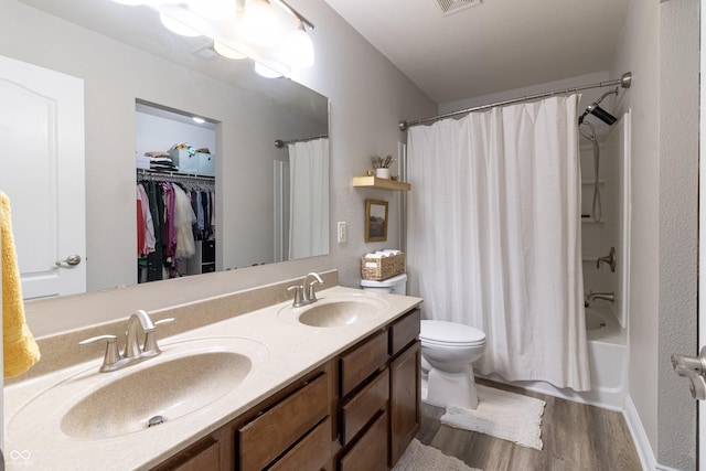 full bathroom with double vanity, toilet, a sink, and wood finished floors