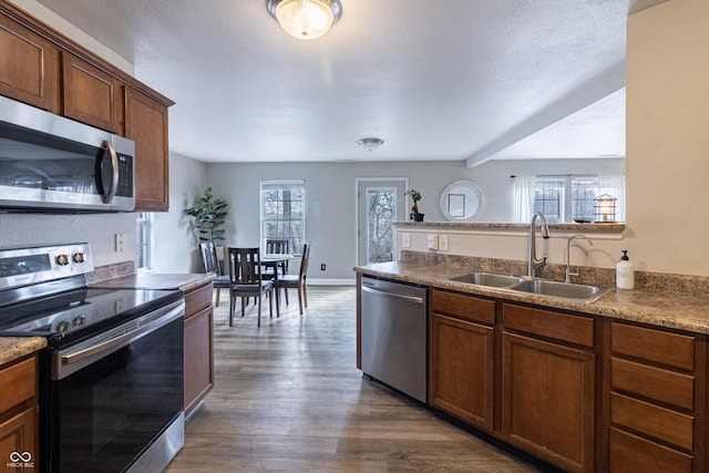 kitchen featuring appliances with stainless steel finishes, a healthy amount of sunlight, dark wood-type flooring, and a sink