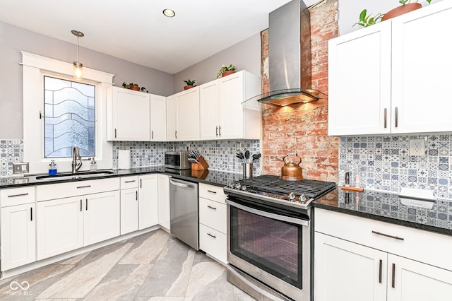 kitchen featuring a sink, backsplash, appliances with stainless steel finishes, white cabinets, and wall chimney range hood