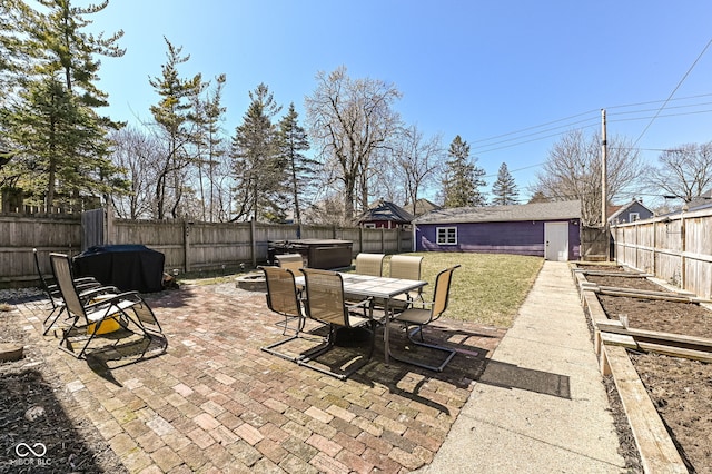 view of patio with an outbuilding, outdoor dining area, and a fenced backyard