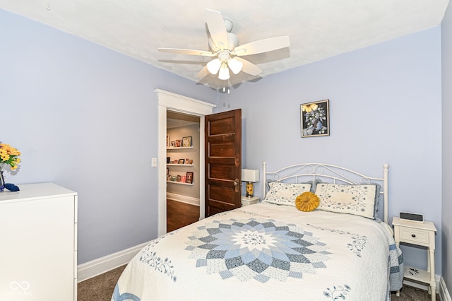 bedroom featuring baseboards, dark colored carpet, and ceiling fan