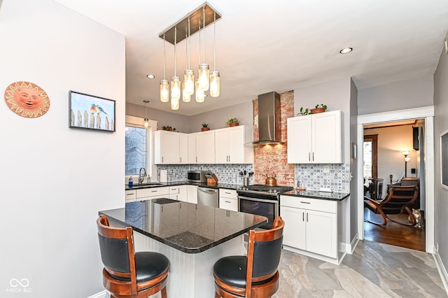 kitchen featuring stainless steel appliances, decorative backsplash, a sink, a kitchen bar, and wall chimney exhaust hood