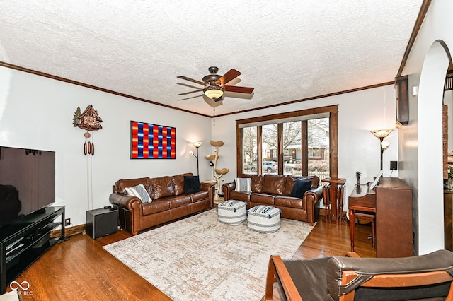 living room featuring a textured ceiling, crown molding, a ceiling fan, and wood finished floors