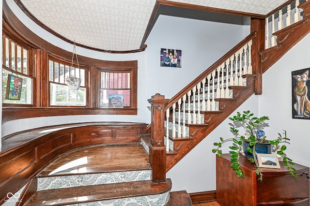 staircase featuring an ornate ceiling and ornamental molding