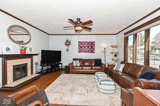 living area featuring a high end fireplace, ornamental molding, ceiling fan, dark wood-type flooring, and a textured ceiling