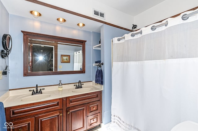 bathroom with curtained shower, double vanity, visible vents, and a sink