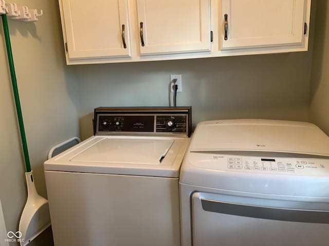 clothes washing area with cabinets and washer and dryer