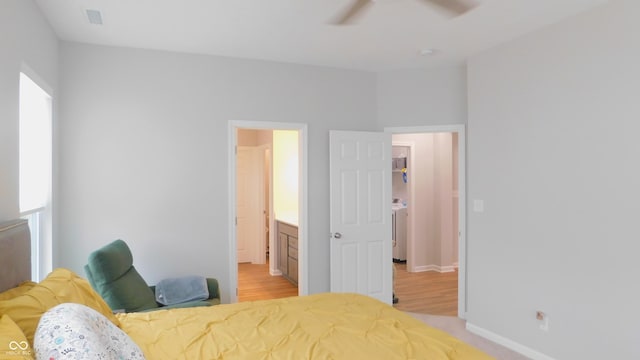 bedroom featuring washer / clothes dryer, light wood-type flooring, and ensuite bathroom