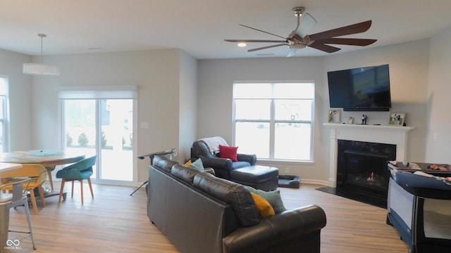 living room with ceiling fan, a wall mounted air conditioner, and light hardwood / wood-style flooring