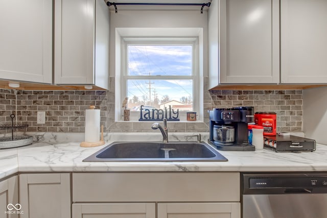 kitchen with white cabinetry, sink, light stone countertops, and dishwasher