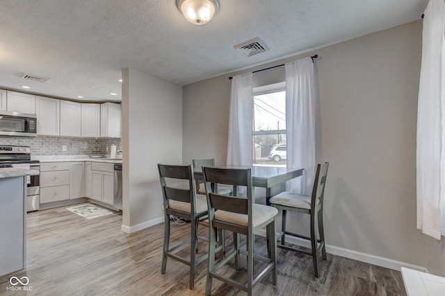 dining space with a textured ceiling and light wood-type flooring