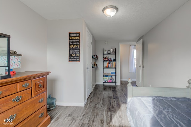 bedroom with a textured ceiling and light hardwood / wood-style floors