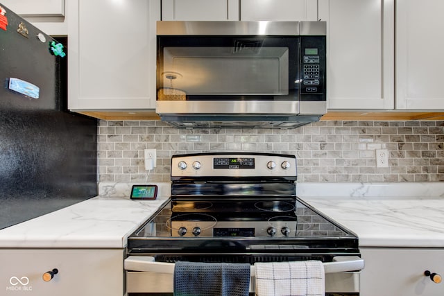 kitchen with tasteful backsplash, stainless steel appliances, and light stone countertops