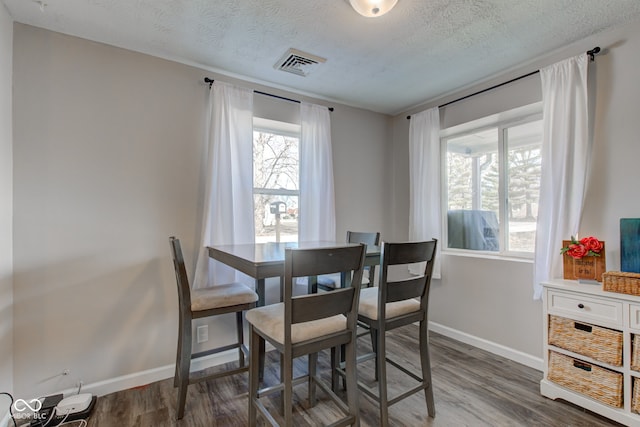 dining room featuring dark wood-type flooring and a textured ceiling