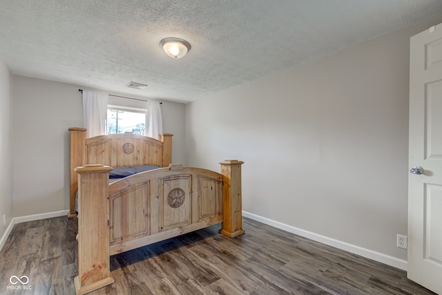 bedroom featuring dark hardwood / wood-style floors and a textured ceiling