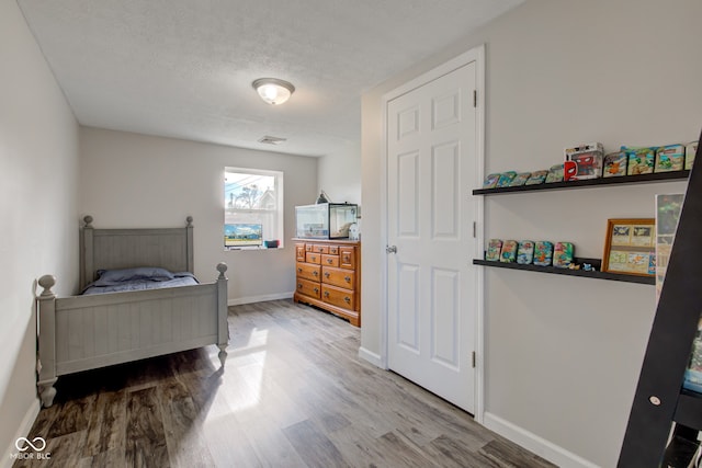 bedroom featuring wood-type flooring and a textured ceiling