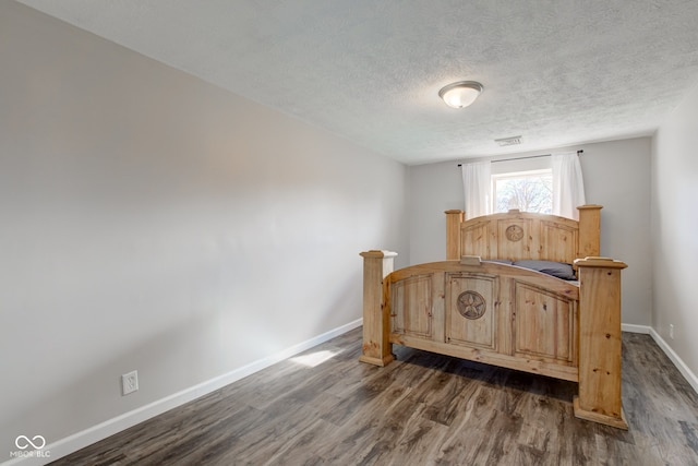 bedroom featuring dark hardwood / wood-style flooring and a textured ceiling