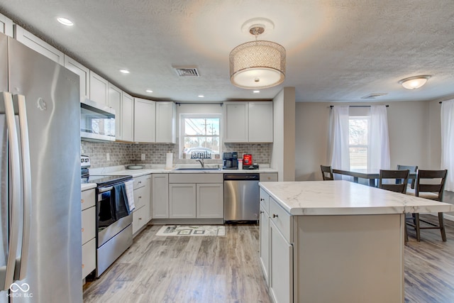 kitchen with appliances with stainless steel finishes, white cabinets, and light wood-type flooring