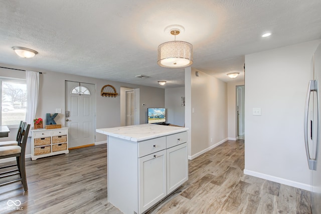 kitchen with white cabinetry, pendant lighting, light hardwood / wood-style flooring, and a textured ceiling