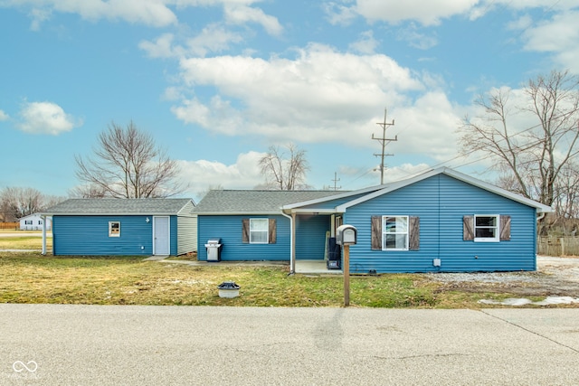 single story home featuring an outbuilding and a front lawn