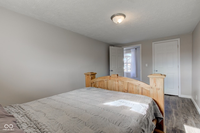 bedroom featuring a textured ceiling and dark hardwood / wood-style flooring