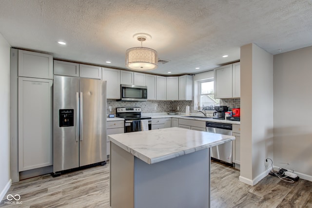 kitchen with tasteful backsplash, decorative light fixtures, a center island, appliances with stainless steel finishes, and white cabinets