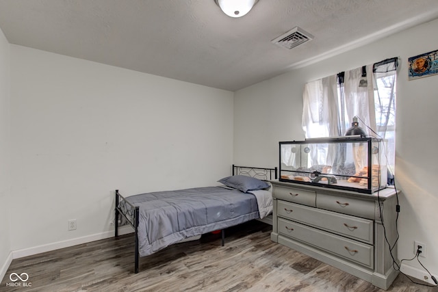 bedroom featuring hardwood / wood-style flooring and a textured ceiling