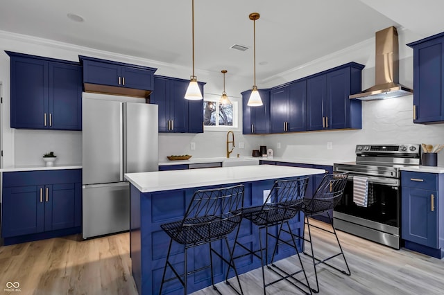 kitchen featuring wall chimney range hood, crown molding, blue cabinetry, appliances with stainless steel finishes, and a center island