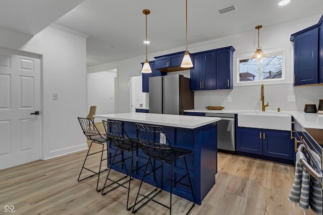 kitchen with blue cabinets, sink, a center island, light hardwood / wood-style flooring, and appliances with stainless steel finishes