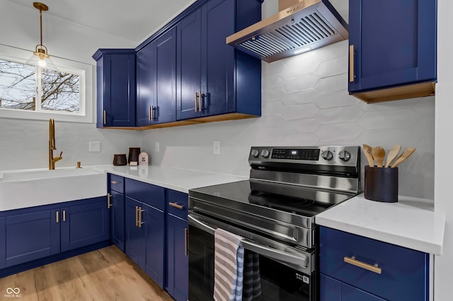 kitchen featuring sink, blue cabinetry, wall chimney range hood, and stainless steel electric range