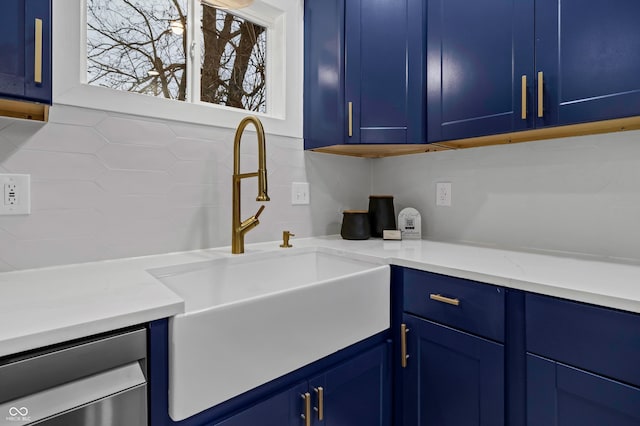 kitchen with light stone counters, sink, decorative backsplash, and blue cabinets