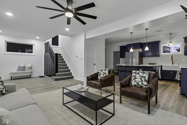 living room with ceiling fan, ornamental molding, indoor wet bar, and light wood-type flooring