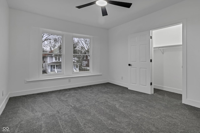 unfurnished bedroom with ceiling fan, dark carpet, and a closet