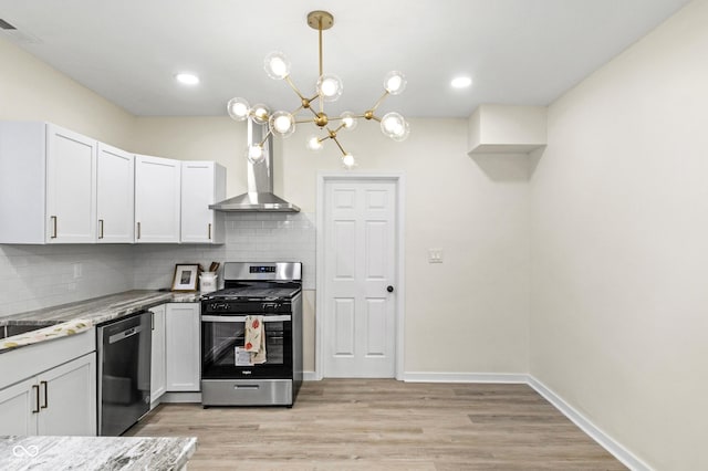 kitchen featuring appliances with stainless steel finishes, decorative light fixtures, white cabinetry, backsplash, and light stone countertops