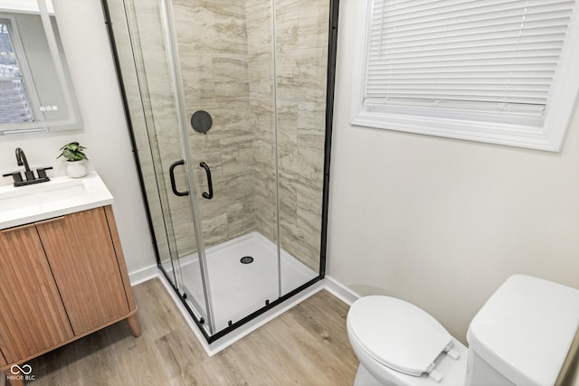 bathroom with an enclosed shower, vanity, wood-type flooring, and toilet