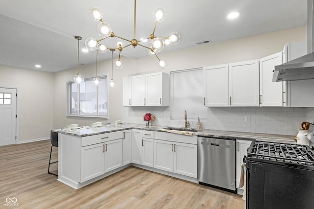 kitchen featuring dishwasher, hanging light fixtures, light stone counters, white cabinets, and wall chimney exhaust hood