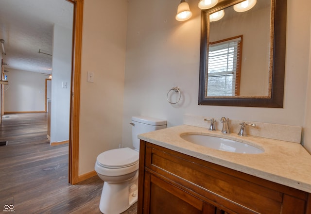 bathroom with wood-type flooring, toilet, and vanity