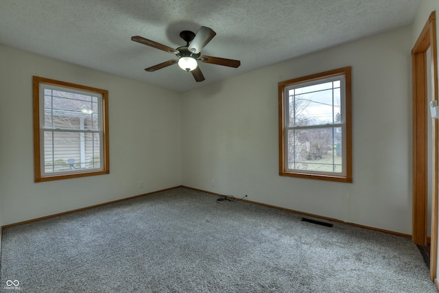 carpeted spare room featuring ceiling fan and a textured ceiling