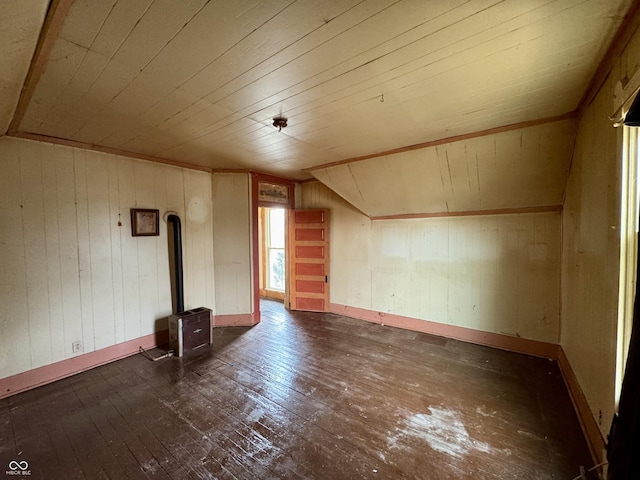 bonus room featuring lofted ceiling, dark hardwood / wood-style floors, a wood stove, and wooden walls