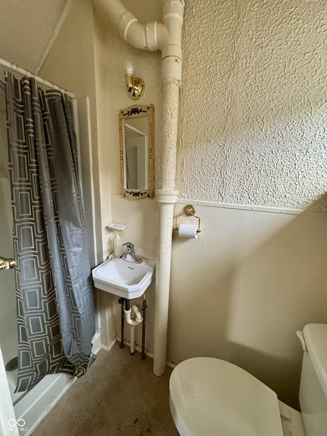 bathroom with walk in shower, sink, and toilet