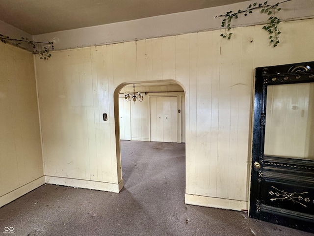 spare room featuring wood walls and dark colored carpet